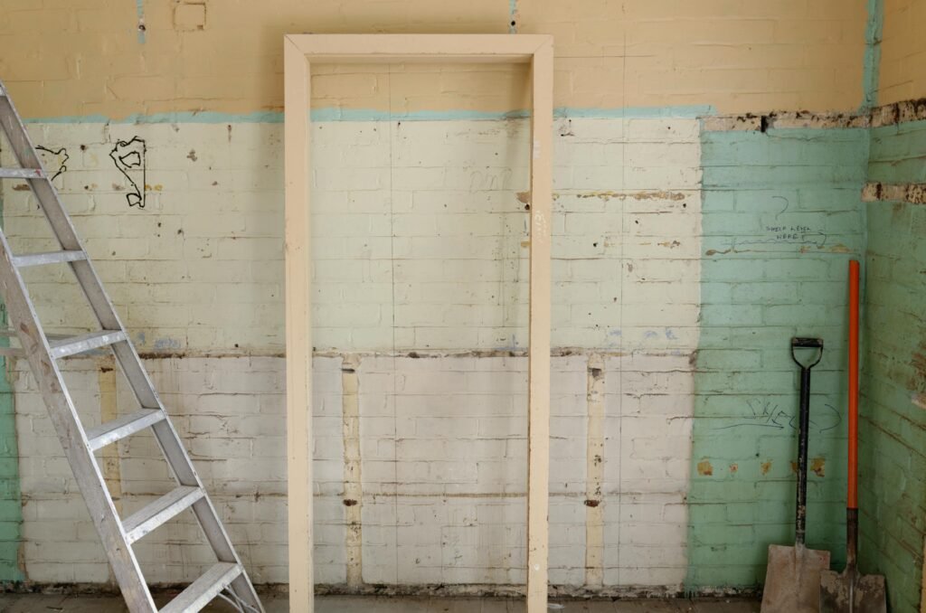 Renovation scene featuring ladder, frame, and tools against partially demolished walls.